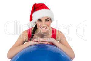 Festive fit brunette leaning on exercise ball