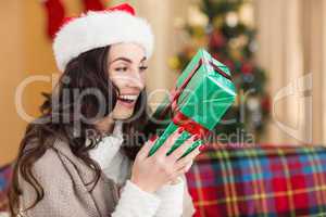 Festive brunette holding gift at christmas