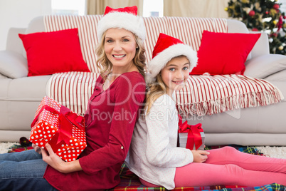 Festive mother and daughter smiling at camera with gifts