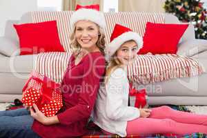 Festive mother and daughter smiling at camera with gifts