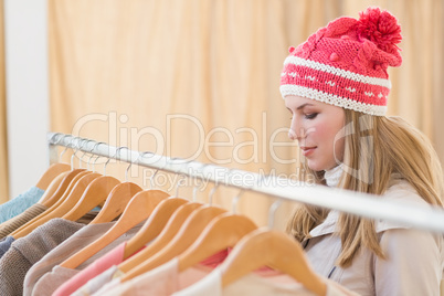 Close up of a pretty blonde looking at clothes on rail