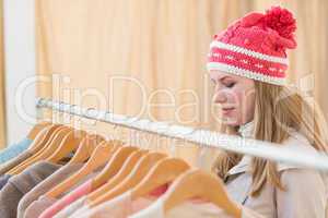 Close up of a pretty blonde looking at clothes on rail