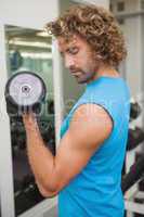 Handsome man exercising with dumbbell in gym