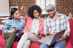 Casual colleagues using laptop on couch