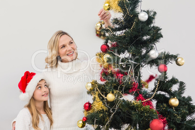 Festive mother and daughter decorating christmas tree