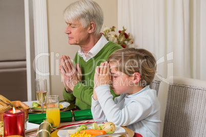 Extended family praying before christmas dinner