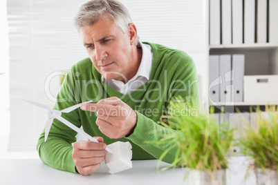 Casual businessman looking at model wind turbines