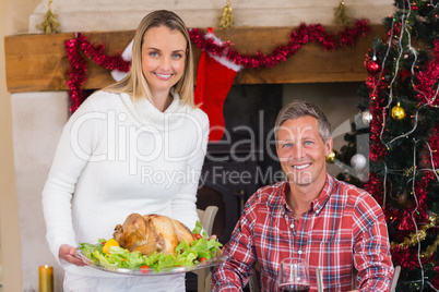 Couple smiling at camera while woman holding roast turkey