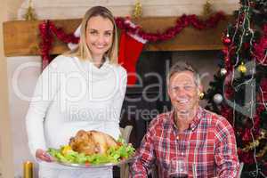 Couple smiling at camera while woman holding roast turkey