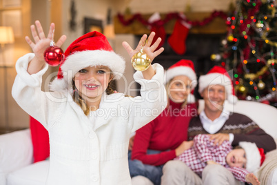 Cute little girl wearing santa hat holding bauble