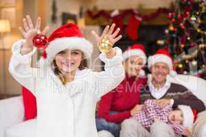 Cute little girl wearing santa hat holding bauble