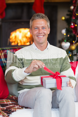 Smiling man opening a gift on christmas day
