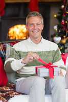 Smiling man opening a gift on christmas day