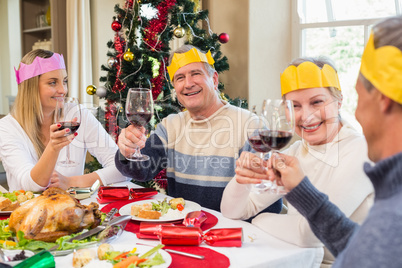 Family in party hat toasting at christmas dinner