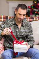 Man opening a gift on the couch at christmas