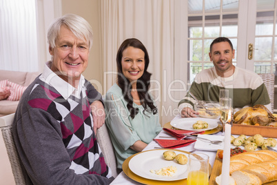 Cheerful family looking at camera during christmas dinner