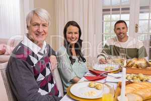 Cheerful family looking at camera during christmas dinner