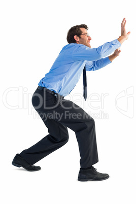 Businessman standing with bent legs and pushing