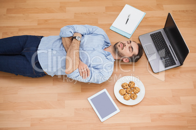 Casual man lying on floor surrounded by his possesions