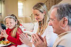 Extended family saying grace before christmas dinner