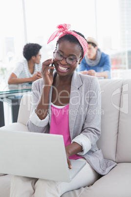 Young creative woman using laptop on couch