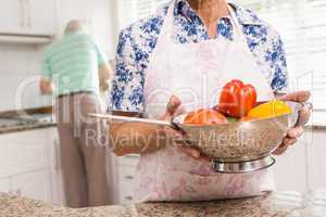 Senior woman showing colander of vegetables
