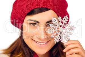 Smiling brunette in hat holding snowflake