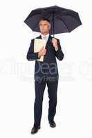 Businessman holding file under umbrella