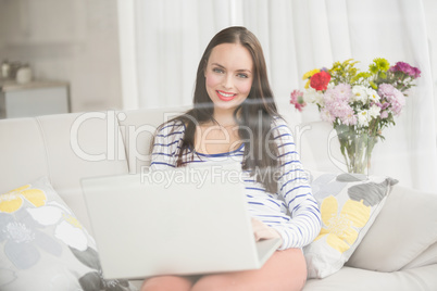 Pretty brunette using laptop on couch