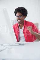 Happy businessman cheering at his desk