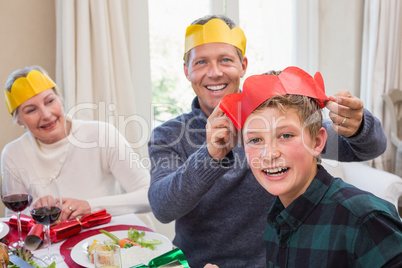 Smiling father putting party hat on sons head