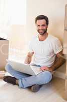 Happy man using laptop surrounded by boxes