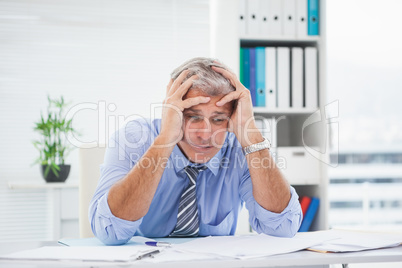 Stressed businessman with head in hands