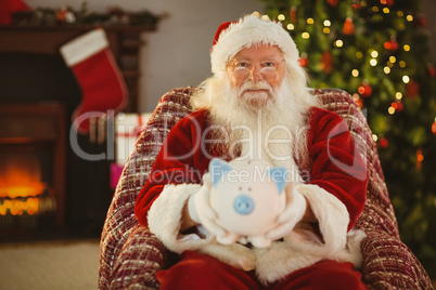 Smiling santa offering piggy bank