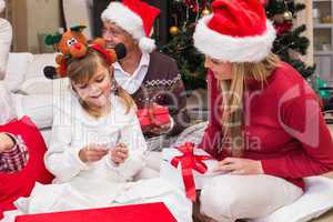 Daughter opening christmas gift with mother