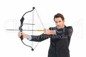 Serious businessman practicing archery looking at camera
