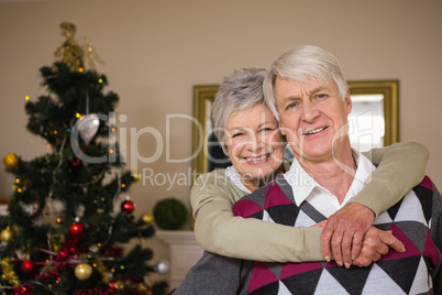 Senior couple smiling beside their christmas tree