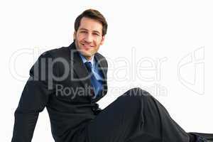 Businessman in suit sitting on floor while looking at camera