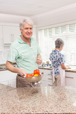 Senior man showing colander of vegetables