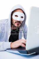 Man wearing mask while hacking into laptop