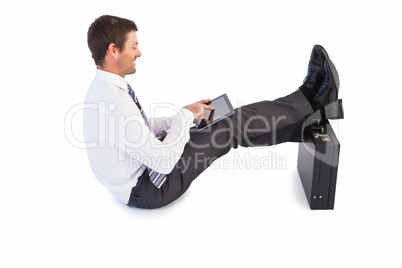 Businessman sitting with feet up while using his tablet