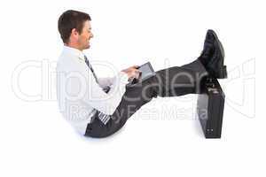 Businessman sitting with feet up while using his tablet