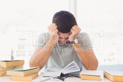 Stressed casual businessman studying at his desk i