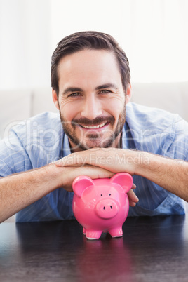 Smiling man laying on the piggy bank
