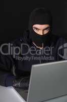 Burglar sitting hacking laptop while looking at camera