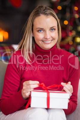 Blonde opening christmas gift while smiling at camera