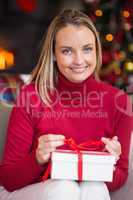 Blonde opening christmas gift while smiling at camera