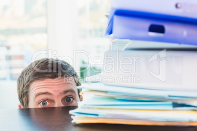 Scared businessman peeking over desk