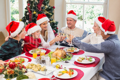 Multi generation family in santa hat toasting each other