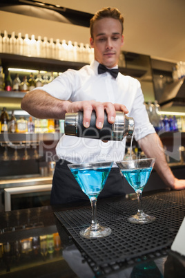 Bartender pouring cocktail into glasses Bartender pouring cocktail into glasses